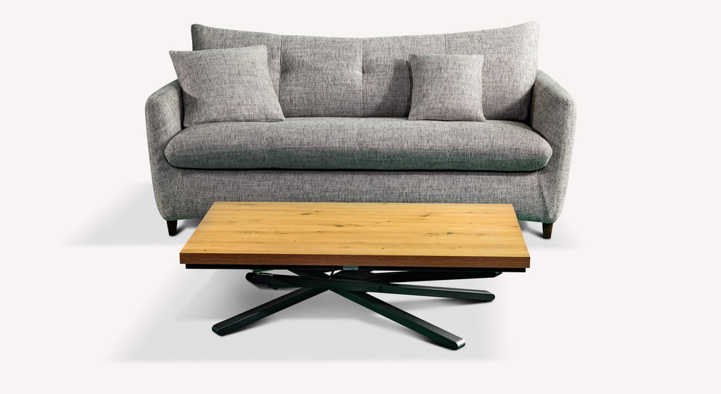 Canapé convertible gris avec coussins, accompagné d'une table basse en bois clair et pieds noirs, style moderne et épuré