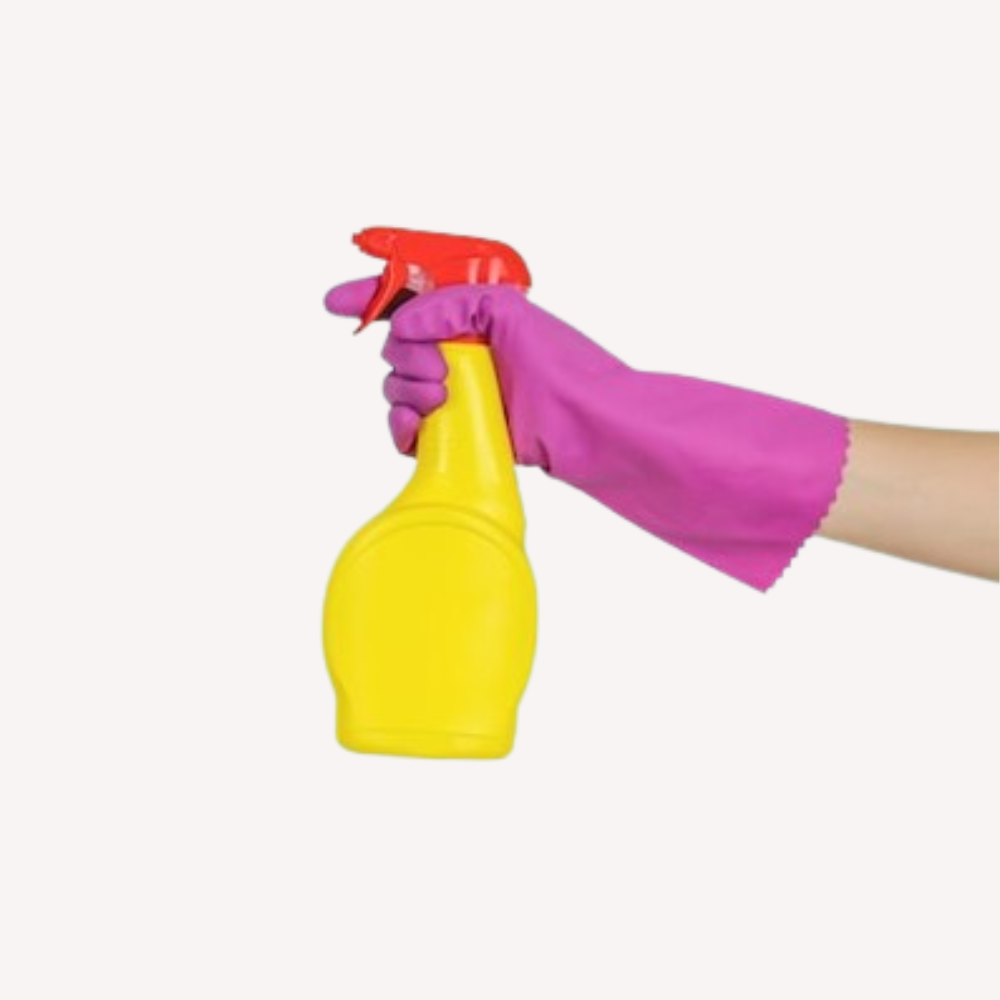 Gant de nettoyage rose tenant un vaporisateur jaune avec une gâchette rouge