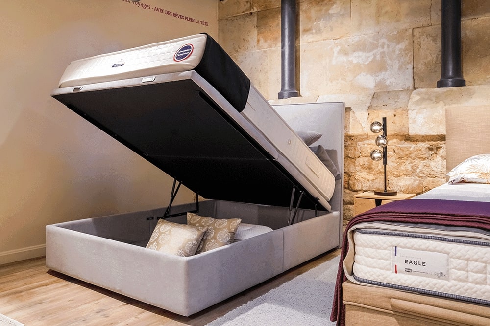 Lit coffre ouvert dans un showroom, exposant un espace de rangement avec des coussins. Contexte : Maison du Convertible, 80 bd de Sébastopol