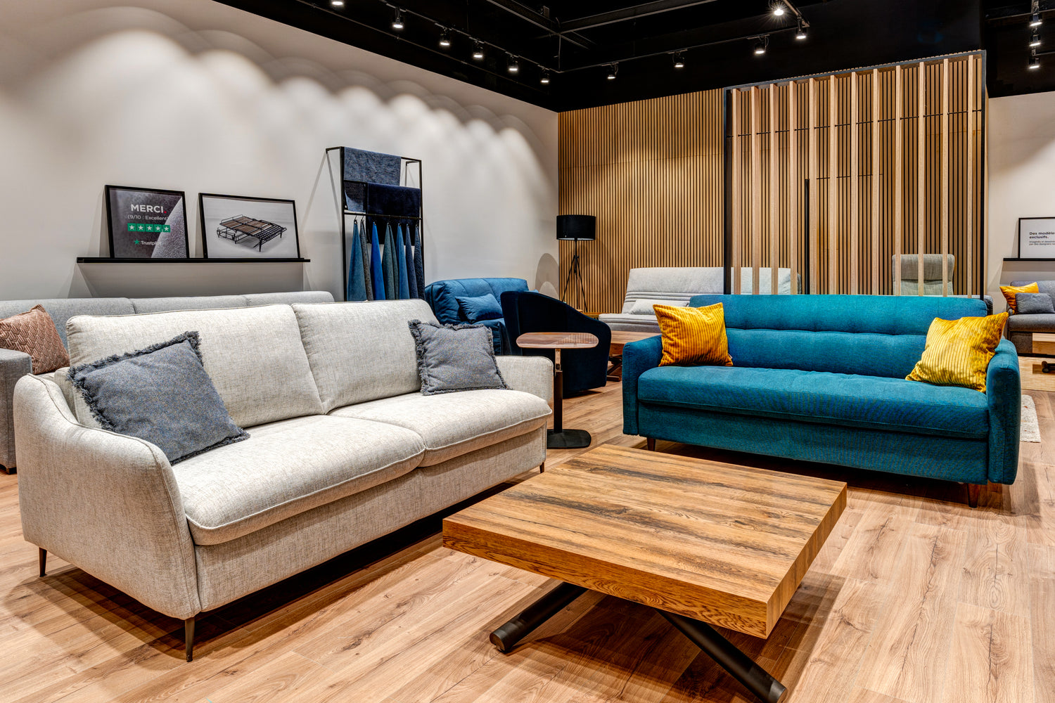 Salon d'exposition de La Maison du Convertible avec canapés modernes, table basse en bois et décorations murales, situé à Plaisir