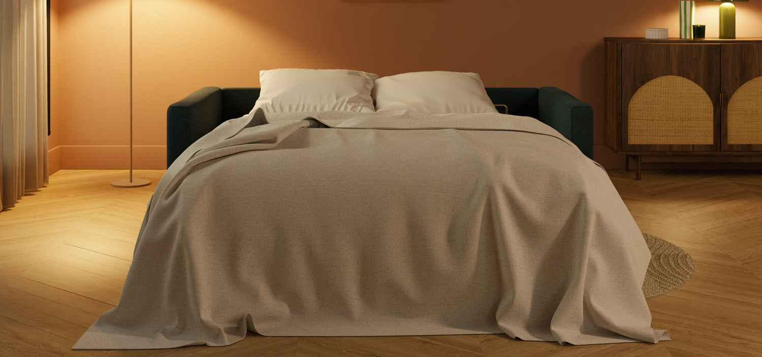 Canapé-lit déplié avec couverture beige dans un salon moderne, éclairage doux et mobilier en bois, optimisé pour le gain de place