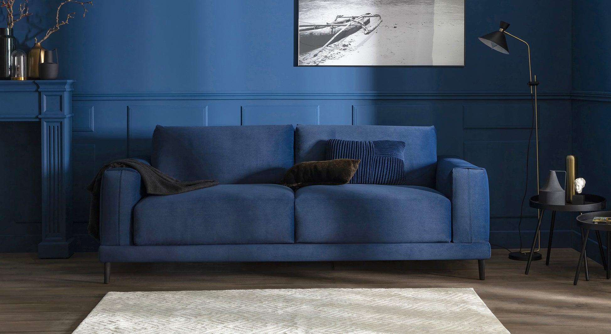 Canapé en velours bleu océan dans un salon élégant, avec des coussins assortis, un tapis clair et une décoration moderne