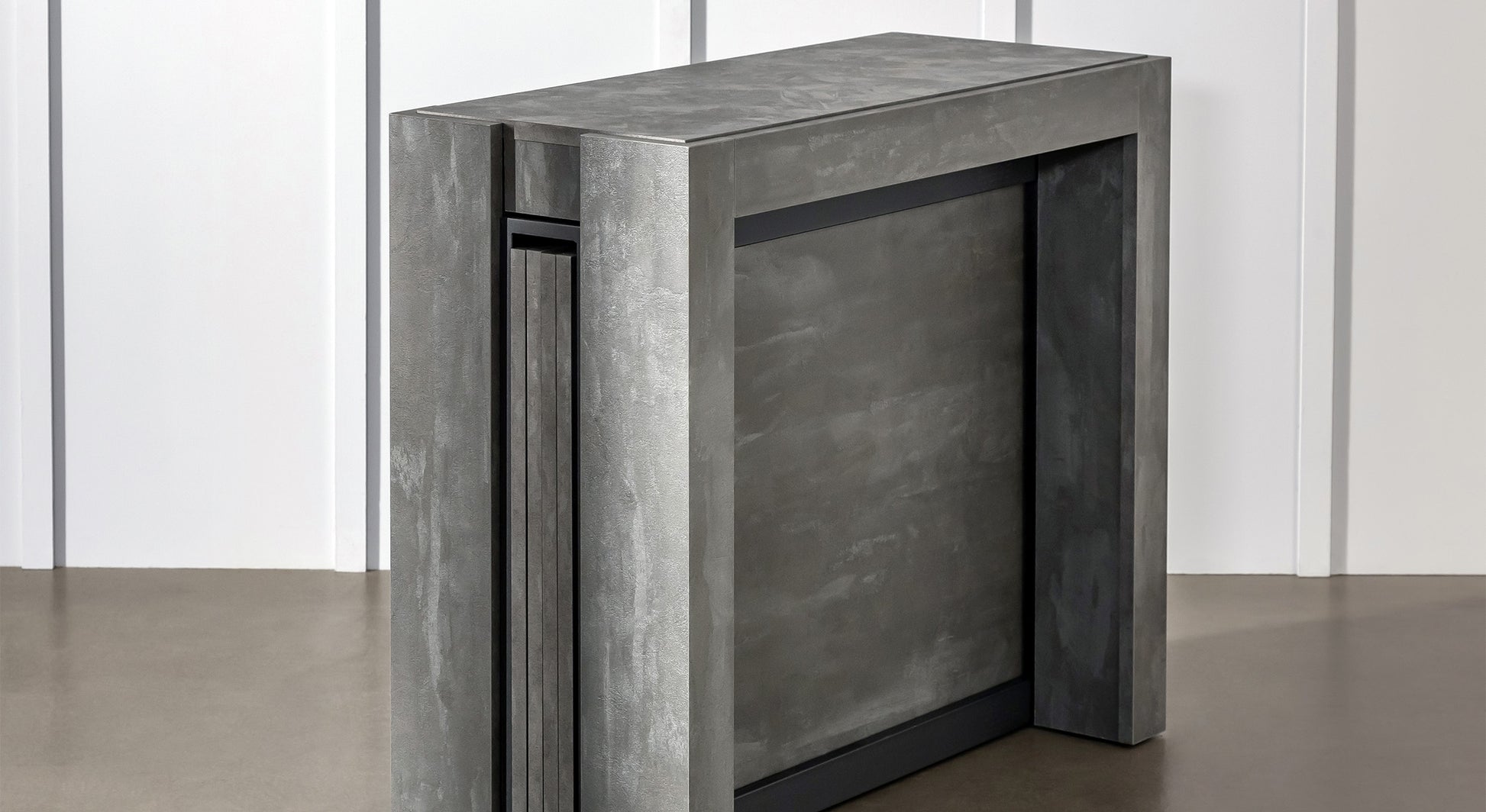 Table extensible compacte en position fermée, finition grise, vue de trois quarts, dans un intérieur moderne