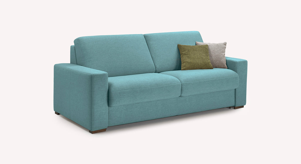 Canapé large en tissu turquoise avec deux coussins, un vert et un beige, sur un fond blanc