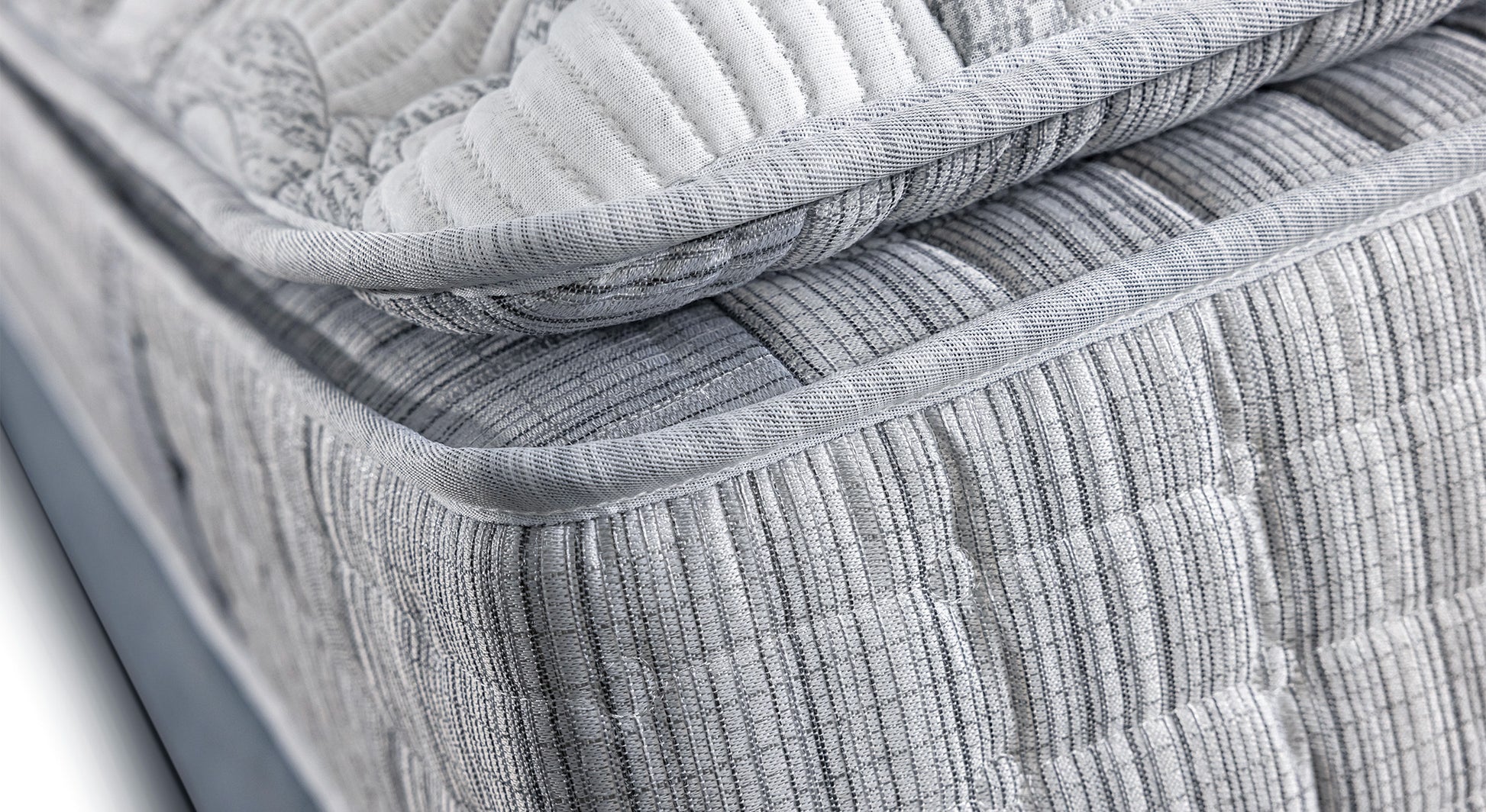 Gros plan sur le coin d'un matelas gris texturé, évoquant un produit de literie de la collection Amsterdam Florence
