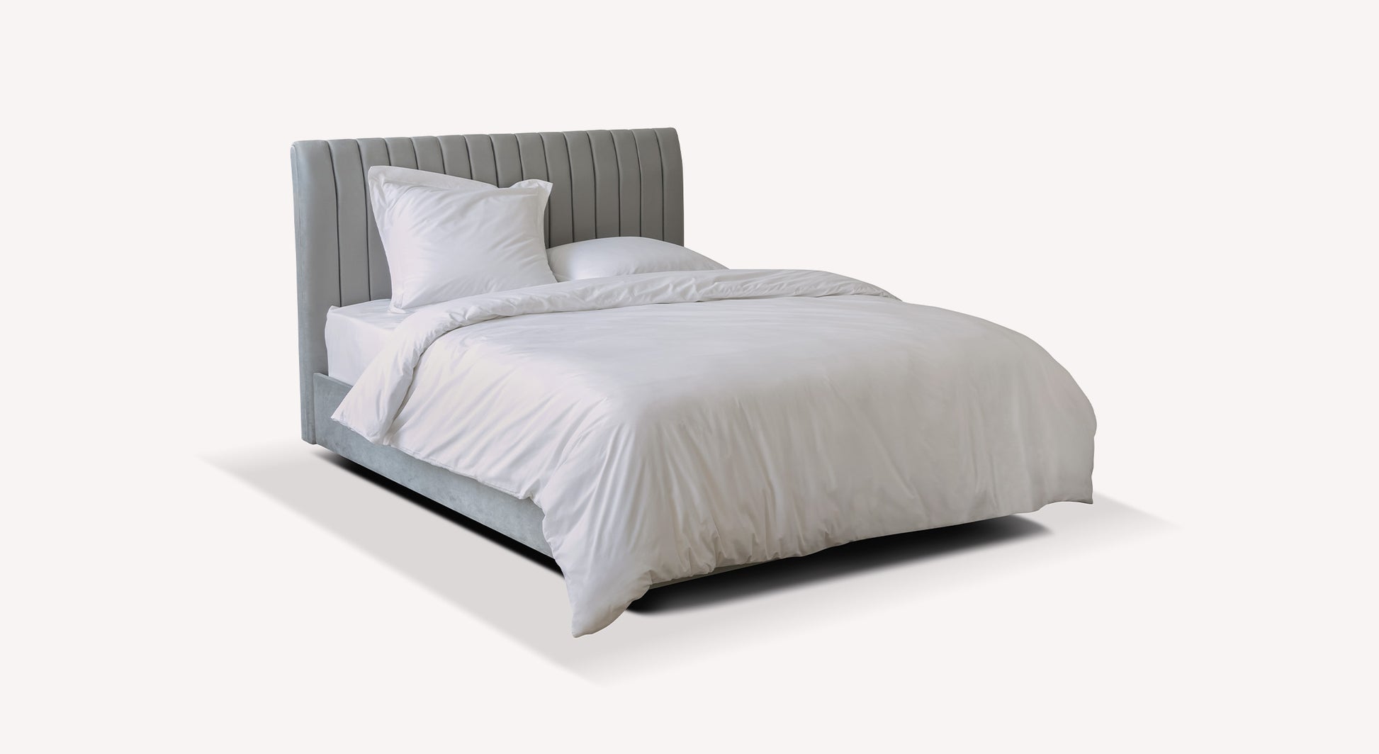 Lit gris avec tête de lit capitonnée, draps blancs, style moderne. Packshot pour Wedpack Amsterdam