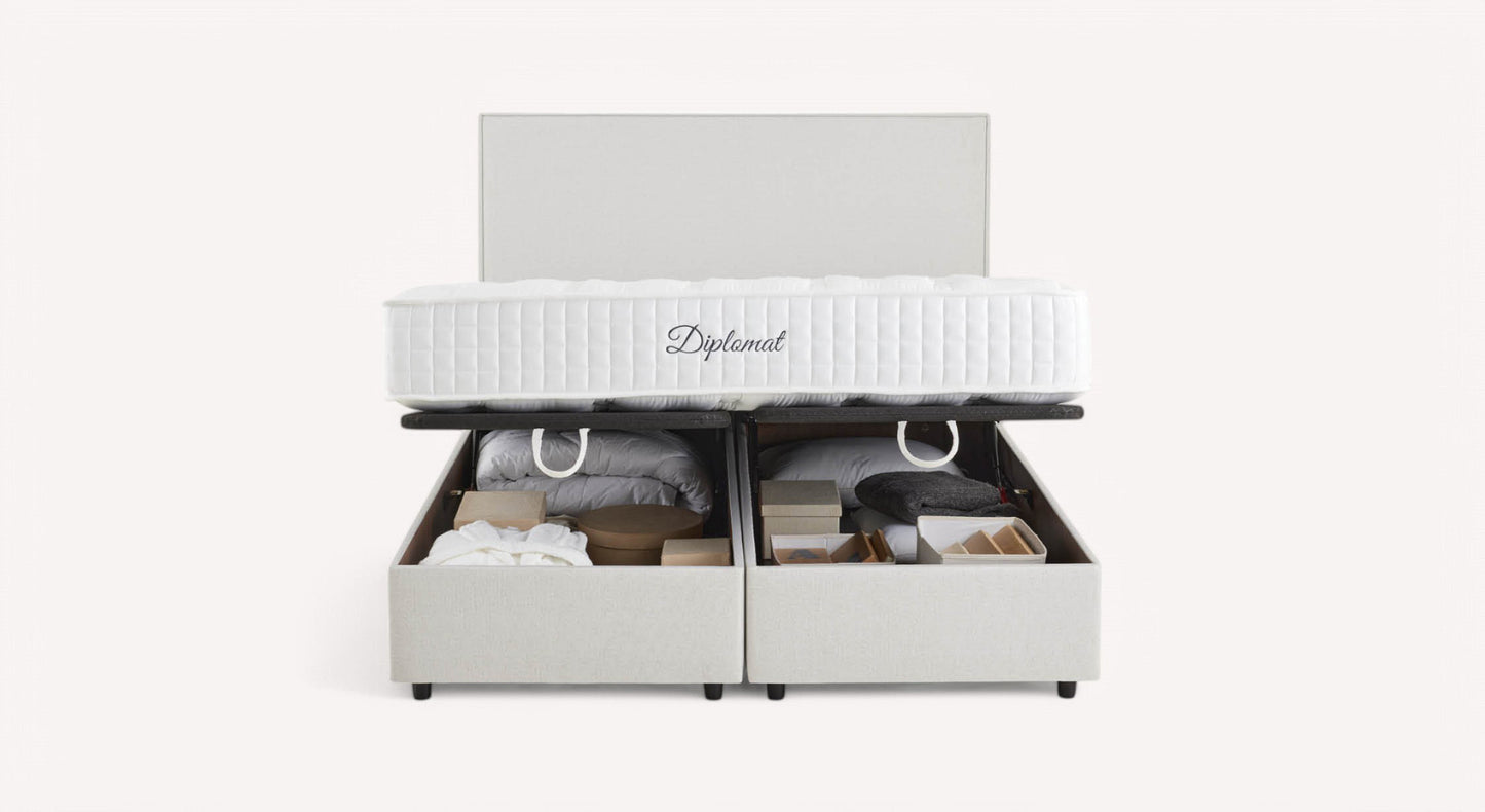 Lit coffre blanc avec matelas "Diplomat", ouvert pour révéler des rangements contenant des couvertures et des boîtes